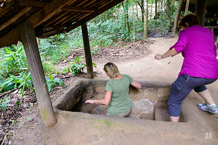 People standing around a way into the Cu Chi tunnels