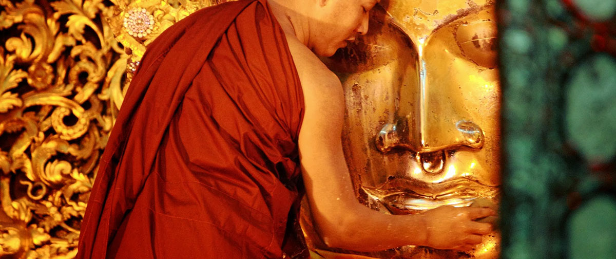 a monk is cleaning Buddha face at Kyaik Khauk Pagoda